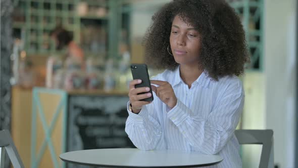 Serious African Businesswoman Using Smartphone in Cafe alt