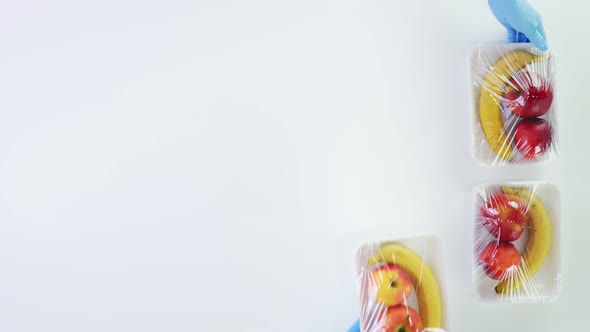 Top View, Hands in Protective Gloves Put Vegetables, Fruits Packages Next To Cardboard Box To