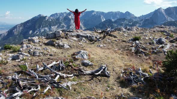 Drone View to Woman in Red Dress on Mountain Top alt