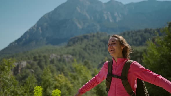 Happy Joyful Woman Tourist Enjoys Breathing Fresh Air in Mountains at Sunny Day alt