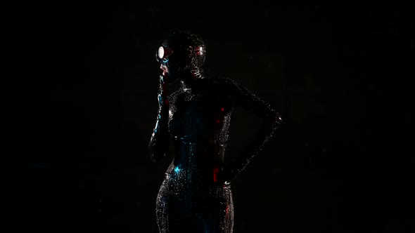 a Woman in a Black Latex Suit Helmet and Glasses Dances on a Dark Background and Licks Palm alt