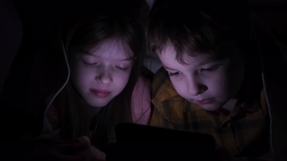 Little Children with a Phone Under the Covers at Night