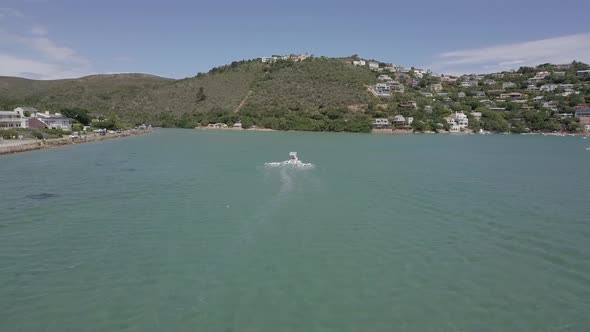 Following aerial of inflatable boat with sun shade in shallow lagoon alt