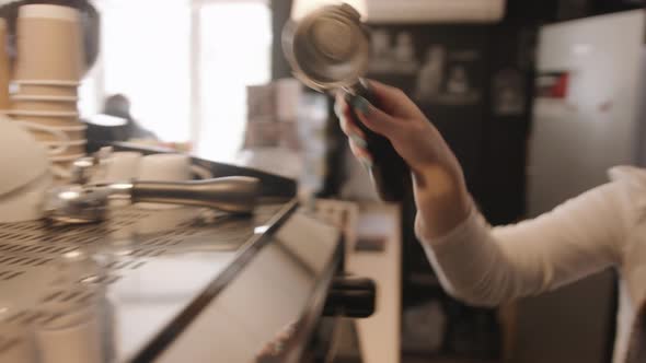 Young Barista Girl in an Apron Prepares Coffee in a Professional Coffee Machine in the Cafe alt