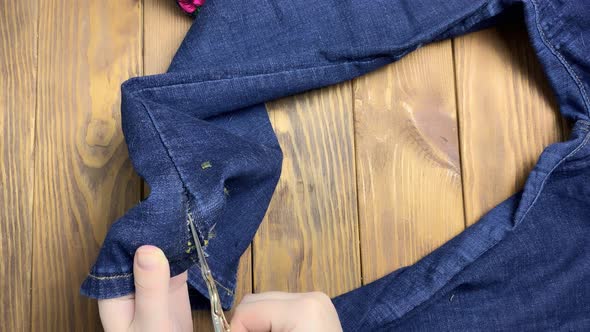 Women's Hands Unpick Seam with Scissors on Jeans