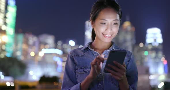 Woman use of mobile phone in Hong Kong city at night  alt
