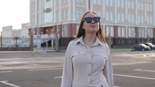 Beautiful Young Girl with Glasses Walks Through the City and Looks Around