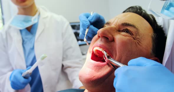 Dentists examining a male patient with tools alt