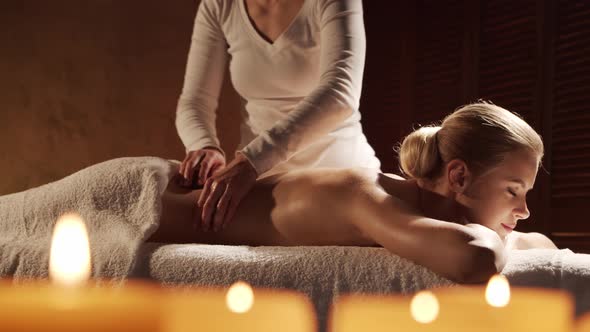 Young, healthy and beautiful woman gets massage therapy in the spa salon. alt