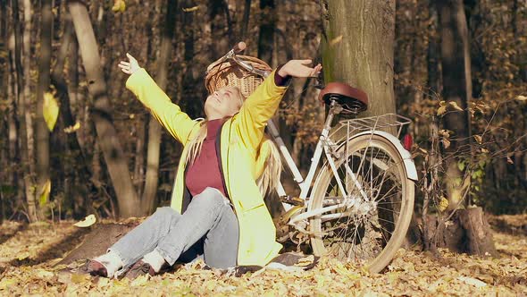 Woman sitting near the tree and bicycle in the autumn forest