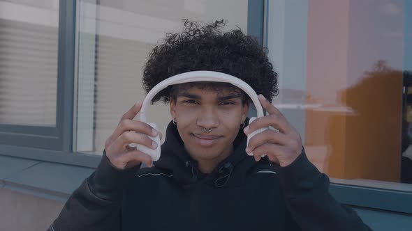 Caucasian Happy Beautiful African American Male in Headphones and Listening to Music Outdoors alt