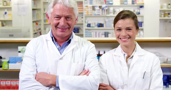 Smiling pharmacists standing with arms crossed in pharmacy alt