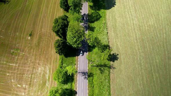 Flying Over A Country Lane With Driving Cars And Vast Farming Area In Warmia-Masuria Province, Polan alt