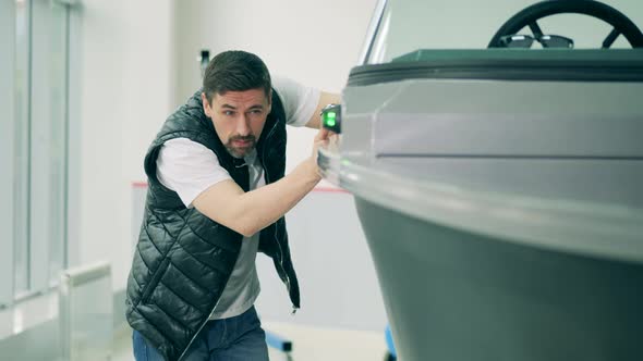 A Man Is Observing a Motorboat in the Showroom alt