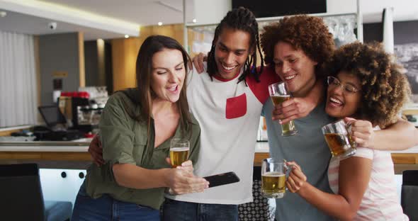 Diverse group of happy friends drinking beers and taking a selfie at a bar alt