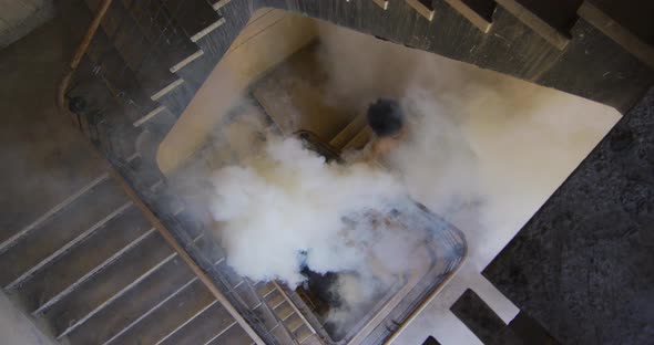 Mixed race woman holding white flare walking down the stairs in an empty building alt
