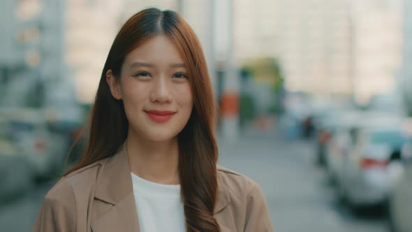 Asian Businesswoman Standing outdoor in street looking at camera and smiling.