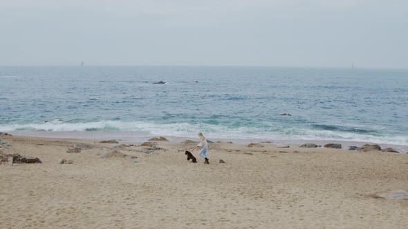 Woman Is Walking With Dog On Sea Coast
