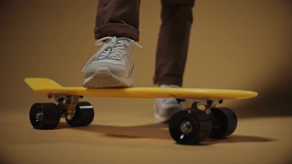 Boy Puts One Foot on a Yellow Penny Board Close Shot