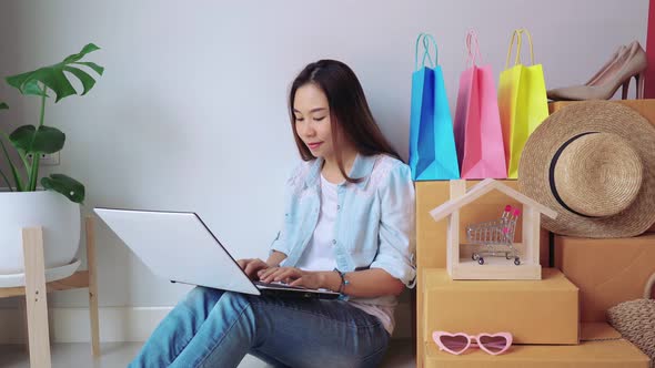 Happy young asian woman with colorful shopping bag at home
