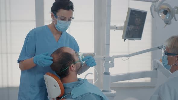Dental Assistant Using Oxygen Mask to Do Anesthesia on Patient alt
