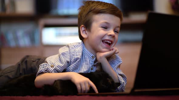 Funny Child with Kitten Using a Laptop at Home. alt