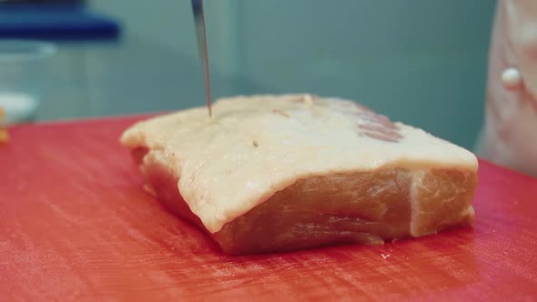 Cook Pierces Holes in a Piece of Meat with a Knife alt