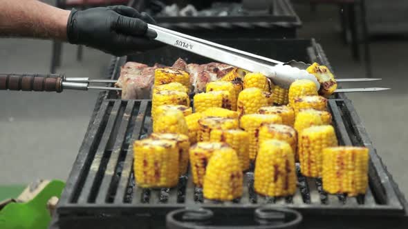 The chef turns the baked corn on the grill. close up. The street food festival.