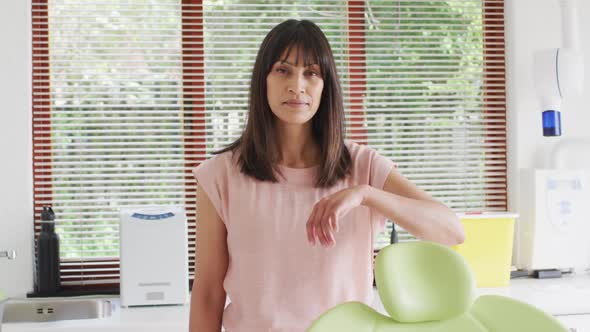 Portrait of smiling biracial female patient looking at camera at modern dental clinic alt
