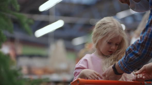 A Man and a Girl in a Store Choose Christmas Decorations alt