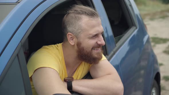 Handsome Young Bearded Caucasian Man Sitting in Car Sticking Out of Window As Cute Little Girl alt
