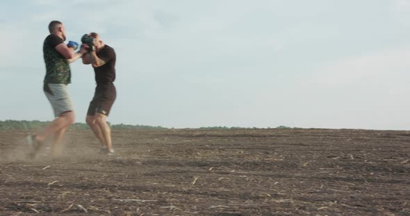 Two Brisk Fighters Training Arm and Legs' Hits Among Soil Field with Dust alt
