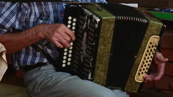 Senior Man Playing with an Old Accordion Outdoor Stage Sitting on Chair.