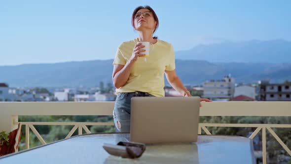 Middleaged Woman Relaxing with Cup of Tea at Home Office on Terrace