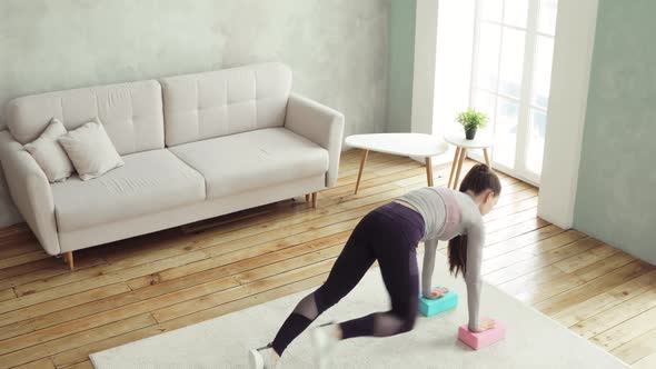 Young Woman Is Making Push-ups From Blocks in Living Room at Home, Top View. alt