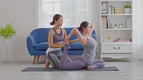 Yoga trainer helping asian woman doing yoga exercise One Legged King Pigeon pose alt