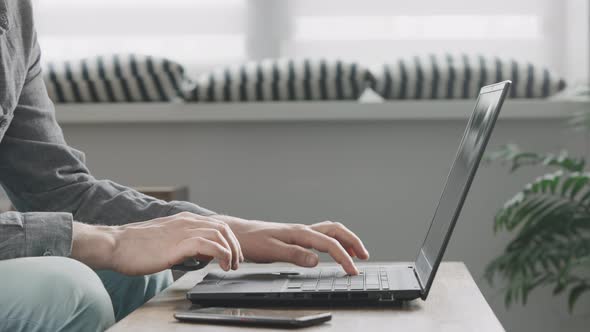Unrecognizable Man Uses His Laptop to Work From Home alt