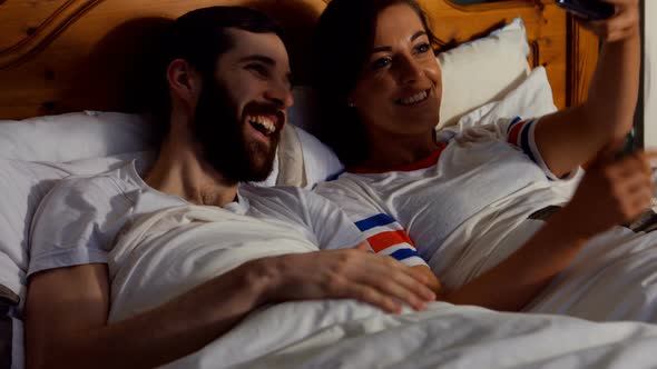 Couple taking selfie from mobile phone in bedroom alt