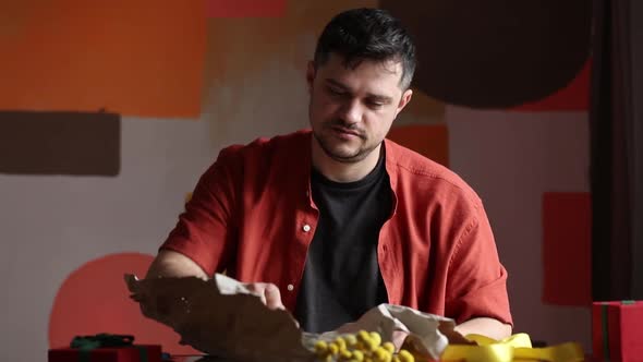 Man wrapping flowers for a Mothers Day at table alt