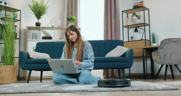 Girl which Resting on the Carpet at Home and Listening Music on Laptop alt