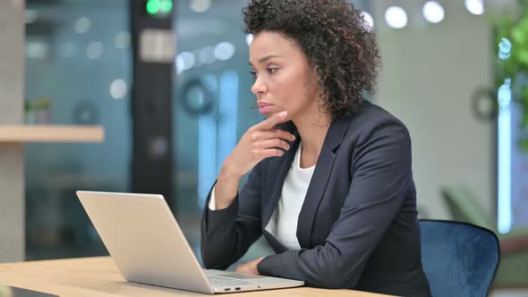 Pensive African Businesswoman Thinking While Working on Laptop alt