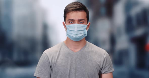 Man on a Protective Mask Looks at the Camera, Portrait of a Man on a City Blurry Background, the alt
