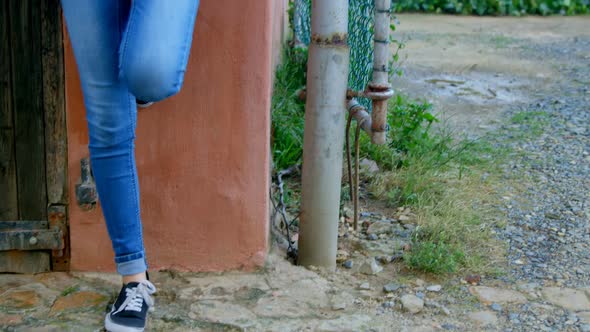 Woman using mobile phone while leaning on wall alt