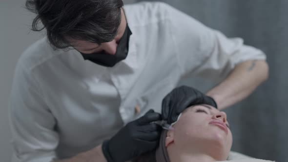 Concentrated Professional Beautician Injecting Rejuvenating Botox Filler with Syringe in Face of alt