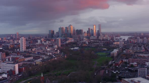 Slow drone shot towards Canary Wharf tower skyscrapers London from north mile end at sunset alt