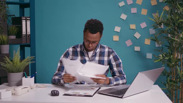 Young Business Man Sorting Out Financial Charts on Papers alt