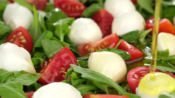 pour olive oil on Italian salad Caprese alt