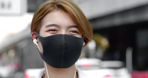 Asian woman wearing earphones and face mask in the city