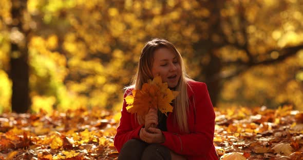 Beautifull Young Mother Goes for a Walk in an Autumn Park