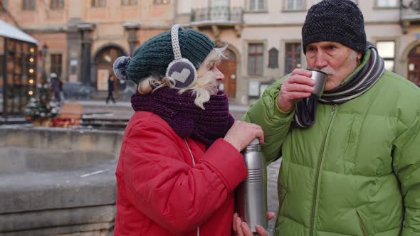 Senior Wife Husband Tourists Drinking From Thermos Enjoying Hot Drink Tea on City Central Street alt